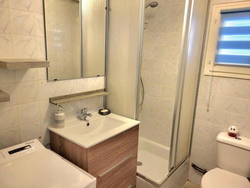 a white bathroom with a sink and a toilet at Jolie Maison Cyprange in Pirou
