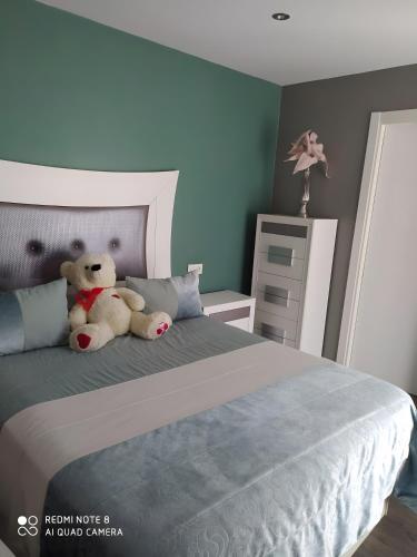 a teddy bear sitting on a bed in a bedroom at Alojamiento Patricia in Igualeja