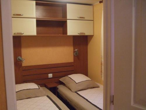 two twin beds in a small room with cabinets at Mobilhome Topaze in Puget-sur-Argens