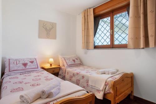 two twin beds in a room with a window at Maison Du Soleil - Bien-être in Saint Vincent