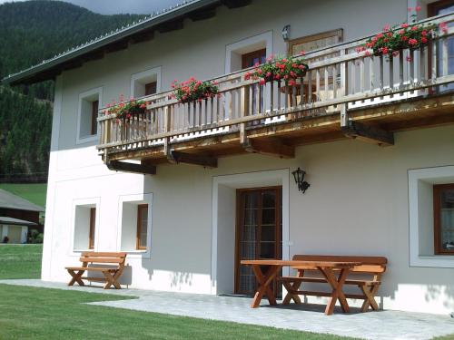 a building with two benches and a balcony with flowers at Marhof Pustertal in Anras
