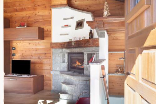 a living room with a fireplace in a log cabin at Maison du coeur - Bien-être in Challand Saint Anselme