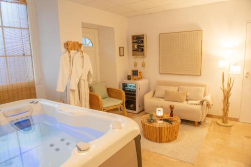 a bathroom with a tub and a living room at Couvent des Cordelières option spa in Vezins