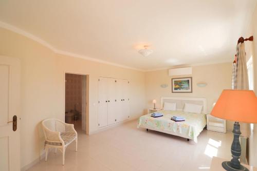 a bedroom with a bed and a chair and a lamp at Villa Carvoeiro Ceu in Lagoa