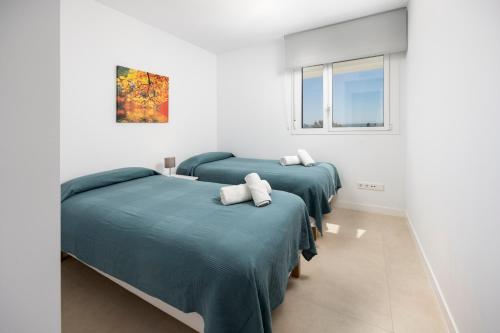 two beds in a room with white walls and windows at Horus 051 in Torre del Mar