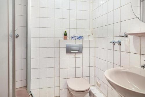 a white tiled bathroom with a toilet and a sink at Gasthaus in Bernkastel-Kues