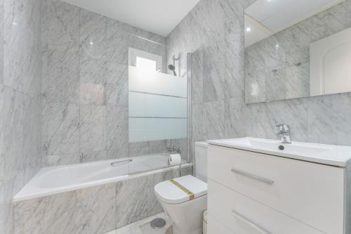 a white bathroom with a sink and a toilet and a tub at 203 Arruzafa Sea View in Málaga