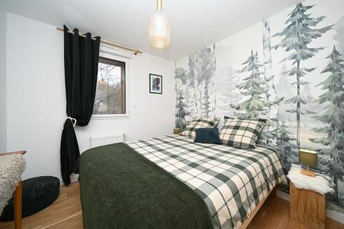 a bedroom with a bed and trees on the wall at Superbe appartement - Face au lac in Génos