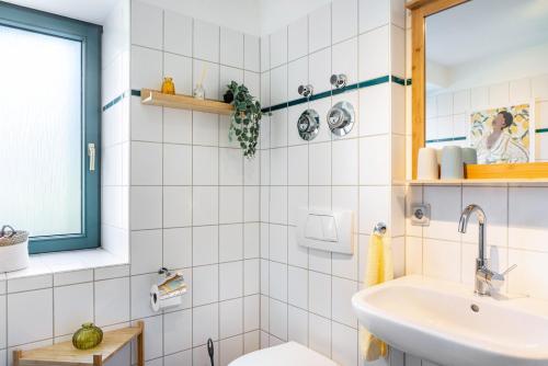 biała, kafelkowa łazienka z umywalką i oknem w obiekcie Ferienwohnung Villa Funcke w mieście Eisenach