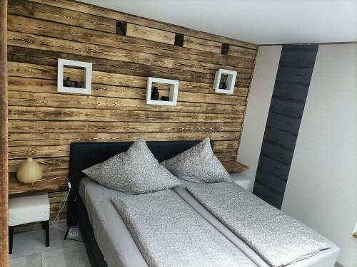 a bedroom with a wooden accent wall with a bed at Waldhaus Hempe in Tabarz