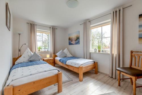 a bedroom with two beds and a chair and windows at Ferienwohnung Anke Volkmann in Offenbüttel