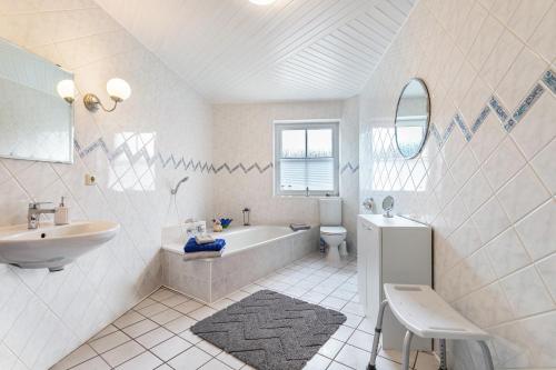 a white bathroom with a tub and a sink at Ferienwohnung Anke Volkmann in Offenbüttel