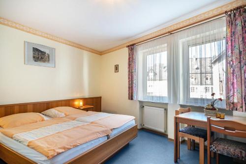 a bedroom with a bed and a desk and windows at Gasthaus in Bernkastel-Kues