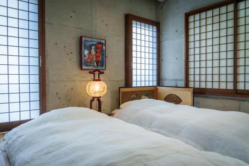 two beds in a room with windows and a lamp at Penthouse KOKO in Miyakonojō