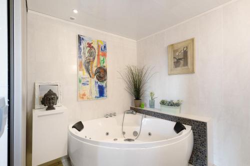 a white bath tub in a bathroom with paintings at Maison de village Puyvalador in Puyvalador