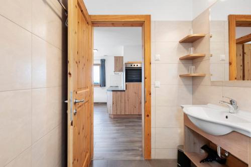 a bathroom with a sink and a mirror and a kitchen at Almhaus Morgenrast in Sarntal