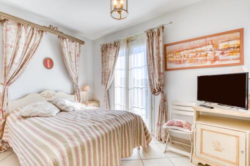 a bedroom with a bed and a flat screen tv at Petite maison Aigues Mortes in Aigues-Mortes
