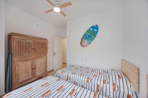 a bedroom with two beds and a surfboard on the wall at Casa Siempreviva in Tarifa