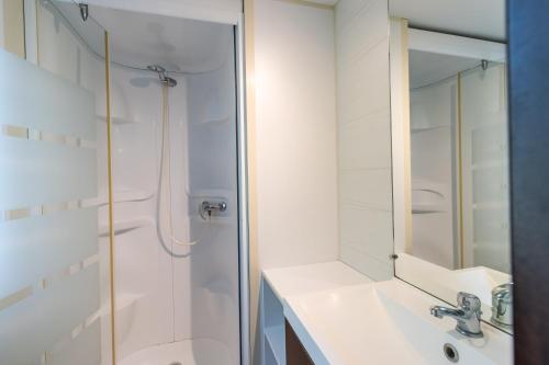 a bathroom with a shower and a sink and a mirror at Mobilhome Le Cocon in Saint-Pompont