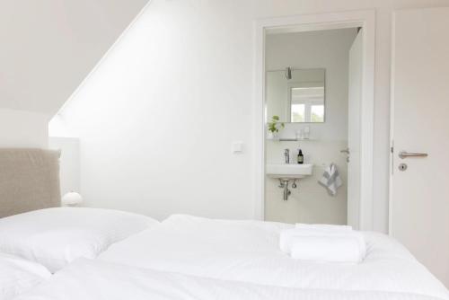 a white bedroom with a bed and a sink at Strand in Böhl