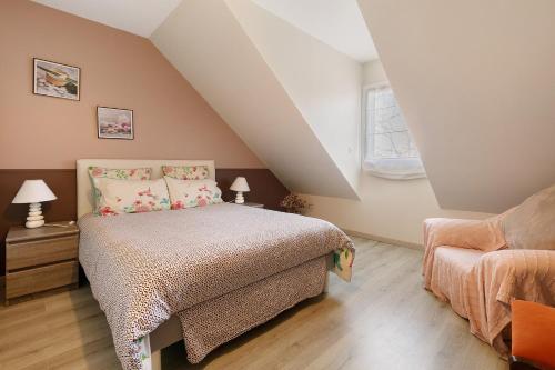 a attic bedroom with a bed and a chair at Chambres d'Hôtes - Les Boubous in Saint-Nazaire