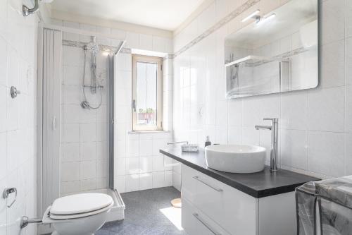 a white bathroom with a sink and a toilet at La Corte Rurale con jacuzzi in Lucca