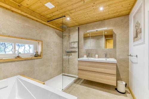 a bathroom with a tub and a sink and a shower at Le Flocon Grand Chalet 4 étoiles in Villard-Reculas
