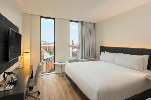 a hotel room with a bed and a desk and windows at INNSiDE by Meliá Manchester in Manchester