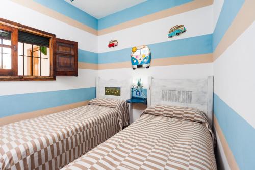 two beds in a room with striped walls at Casa Basallote in El Palmar