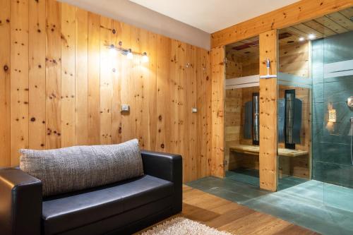 a room with a black couch and a glass shower at La Plates App Domesdi in Ortisei
