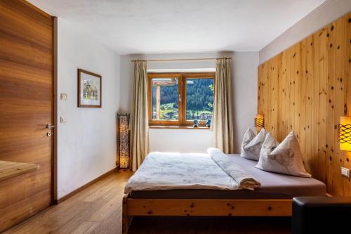 a bedroom with a bed with a wooden headboard and a window at La Plates App Domesdi in Ortisei