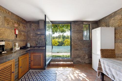 a kitchen with a large window and a refrigerator at Casa de Andrães Pomar in Marco de Canaveses