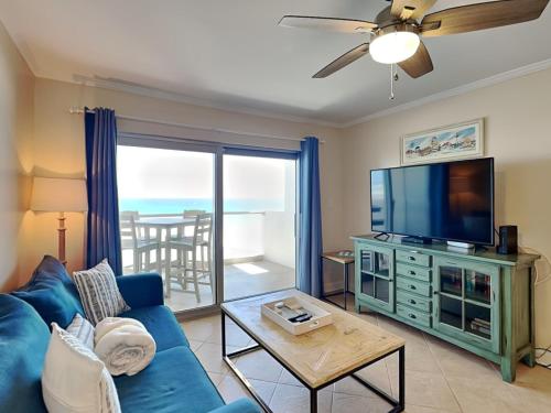 a living room with a blue couch and a flat screen tv at Regency Towers #802 East in Pensacola Beach
