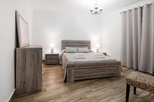a white bedroom with a bed and a mirror at Windmill Beach House in Ribeira Grande