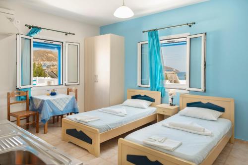 two beds in a room with two tables and windows at Studios Ninemia Serifos 4 in Livadi
