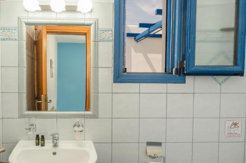 a bathroom with a sink and two blue windows at Studios Ninemia Serifos 4 in Livadi
