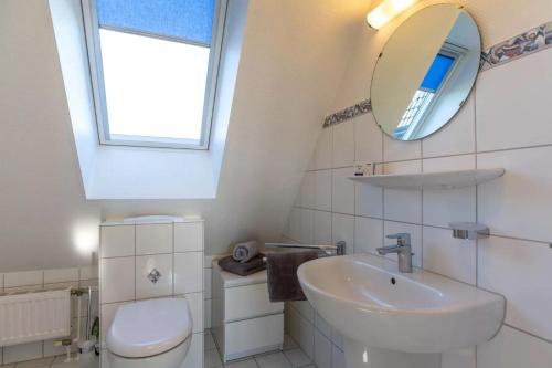 a white bathroom with a sink and a mirror at Urlaub an der Nordermühle in Pellworm