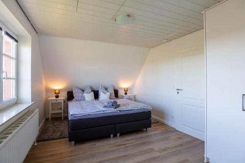 a bedroom with a bed in a white room at Urlaub an der Nordermühle in Pellworm
