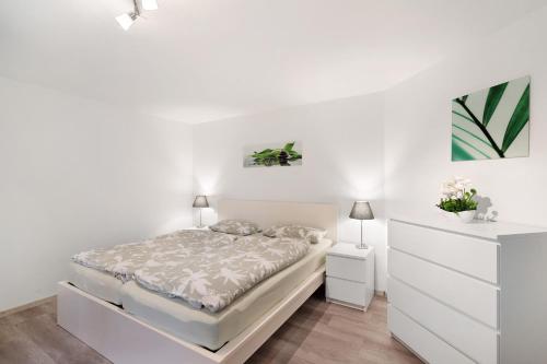 a white bedroom with a bed and a dresser at Hochwertige Ferienwohnung Ötigheim in Ötigheim