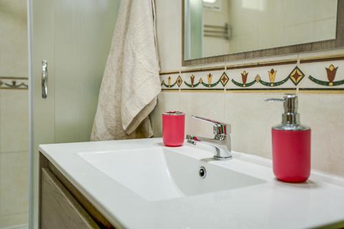 a bathroom sink with two red cups on it at 2a Francesca in Vecindario