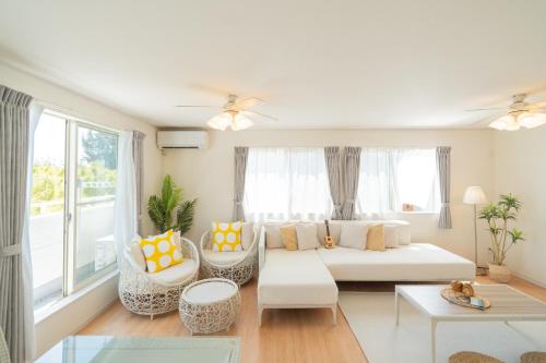 a living room with a white couch and windows at 照間Terumaの美しい海Mareまで徒歩30秒リビング広々快適 TERUMAREテルマーレ in Uruma
