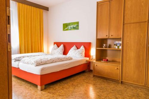 a bedroom with a bed with an orange headboard at Ferienwohnung Lanz 3 in Lana