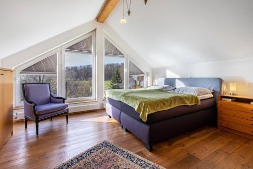 a bedroom with a bed and a chair and windows at Panoramaferienhaus Sorpesee, 120qm in Sundern