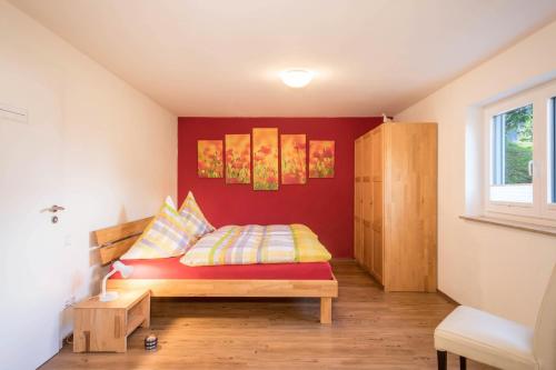 a bedroom with a bed with a red wall at Ferienhof Weber Wohnung Fichte in Neukirch