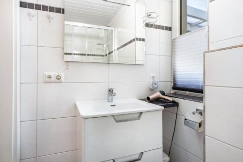 a white bathroom with a sink and a mirror at Prerow Am Deich - Ferienwohnung 1 in Prerow
