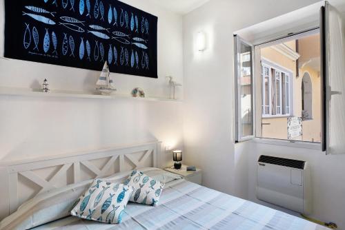 a white bedroom with a bed and a window at Casa di Ali in Imperia