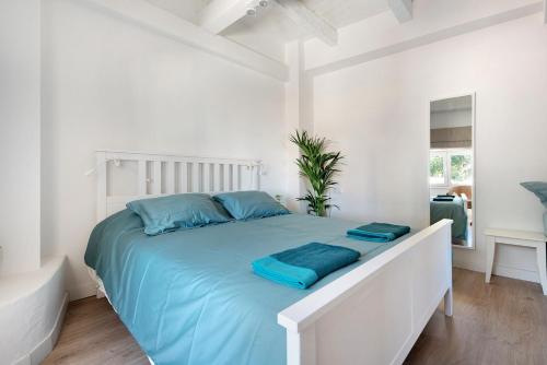 a white bedroom with a large bed with blue pillows at Casa Sol 21 B Garachico in Garachico