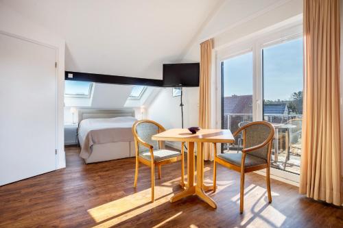 a hotel room with a table and chairs and a bed at Haus Ostseesonne in Baabe