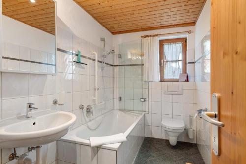 a bathroom with a sink and a tub and a toilet at Haus Verdandi in Sibratsgfäll