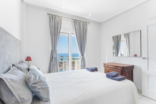 a white bedroom with a bed and a window at Casa del Sol Premium Cabo Roig in Orihuela